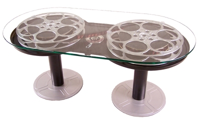 A coffee table consistint of two movie reels holding up a glass top